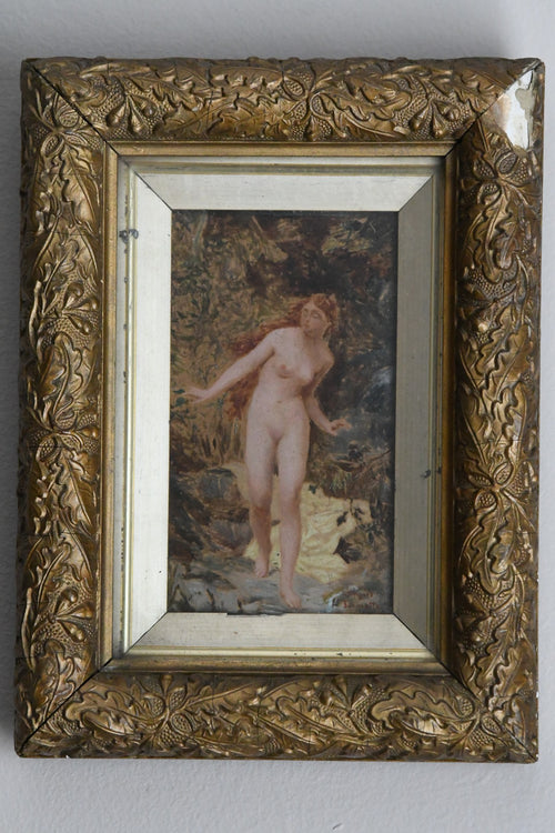 Decorative gold frame with a painting of a nude figure with a woodlands background