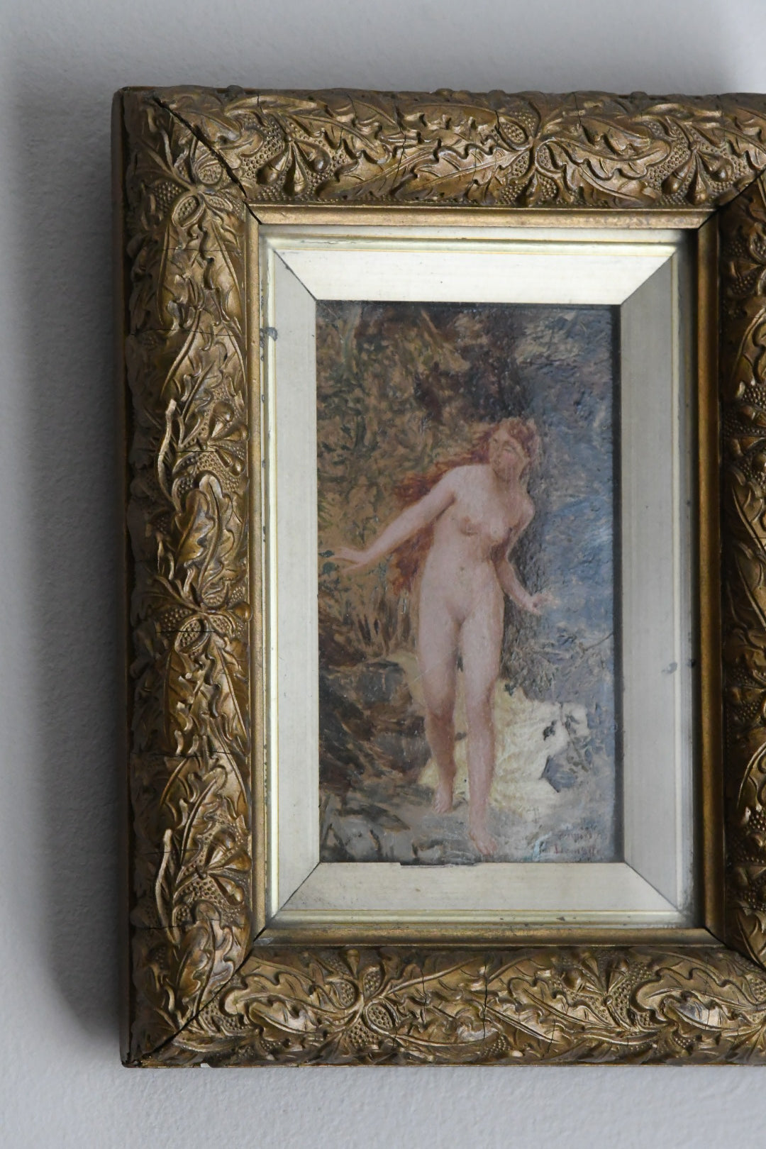 Decorative gold frame with a painting of a nude figure with a woodlands background